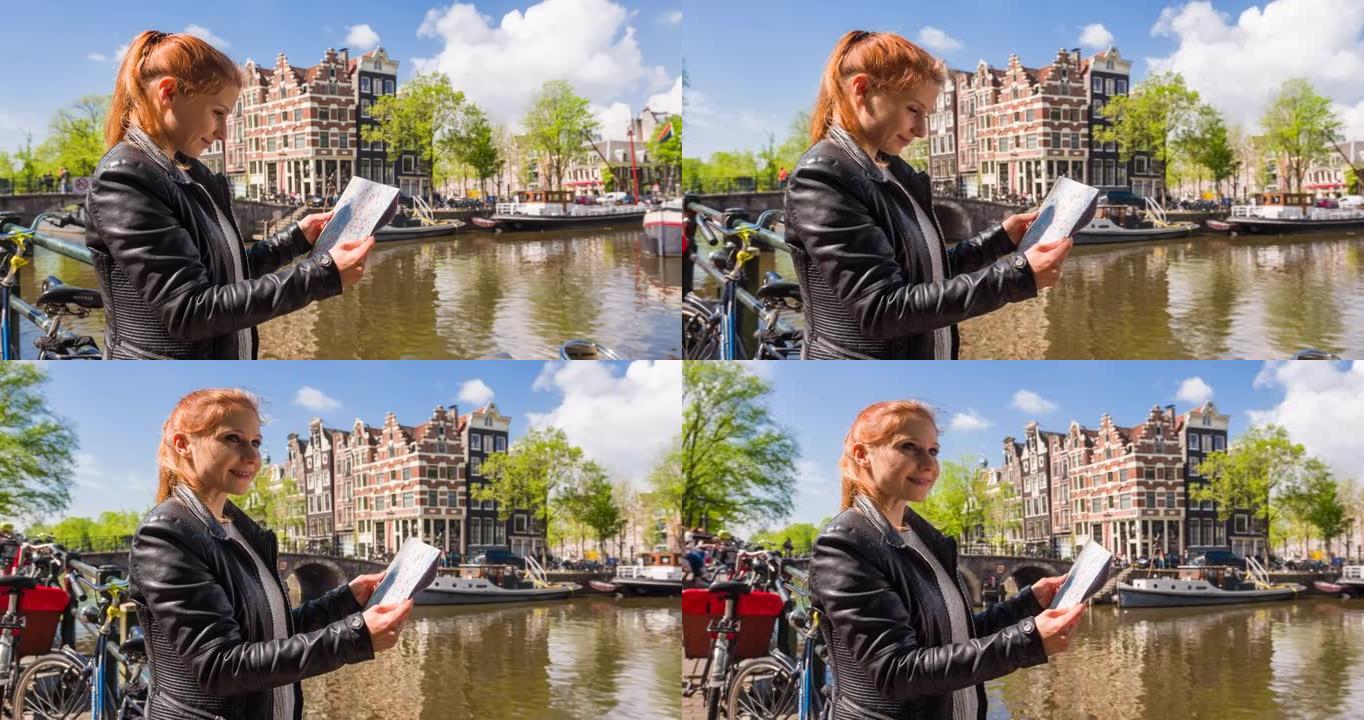 快乐的女人站在阿姆斯特丹运河旁边，拿着城市地图，欣赏美丽阳光明媚的日子里的景色