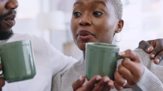 幸福的黑人夫妇在家里喝咖啡和结缘，在客厅里一起说笑。年轻的男人和女人享受他们的关系，放松和开玩笑，分