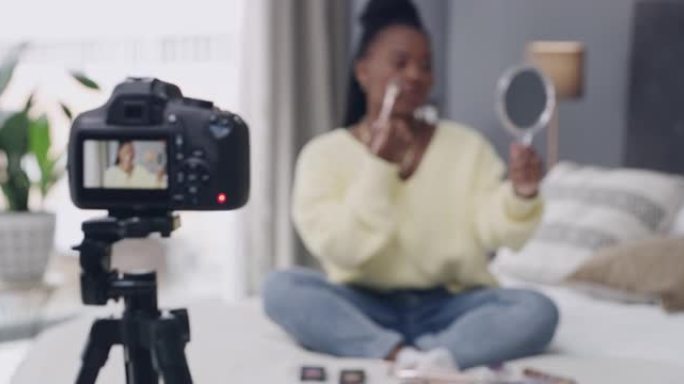 4k视频片段，一名年轻女子坐在公寓的床上做化妆教程vlog