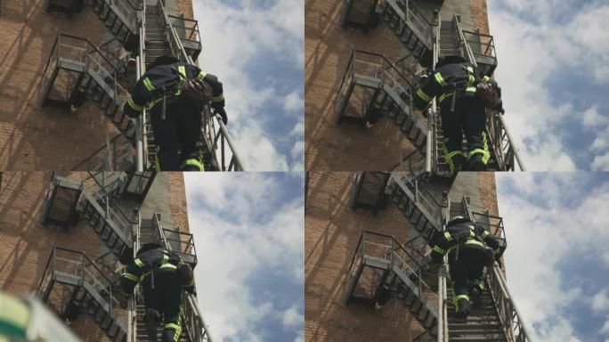 无法识别的消防员在砖砌建筑物外攀爬梯子