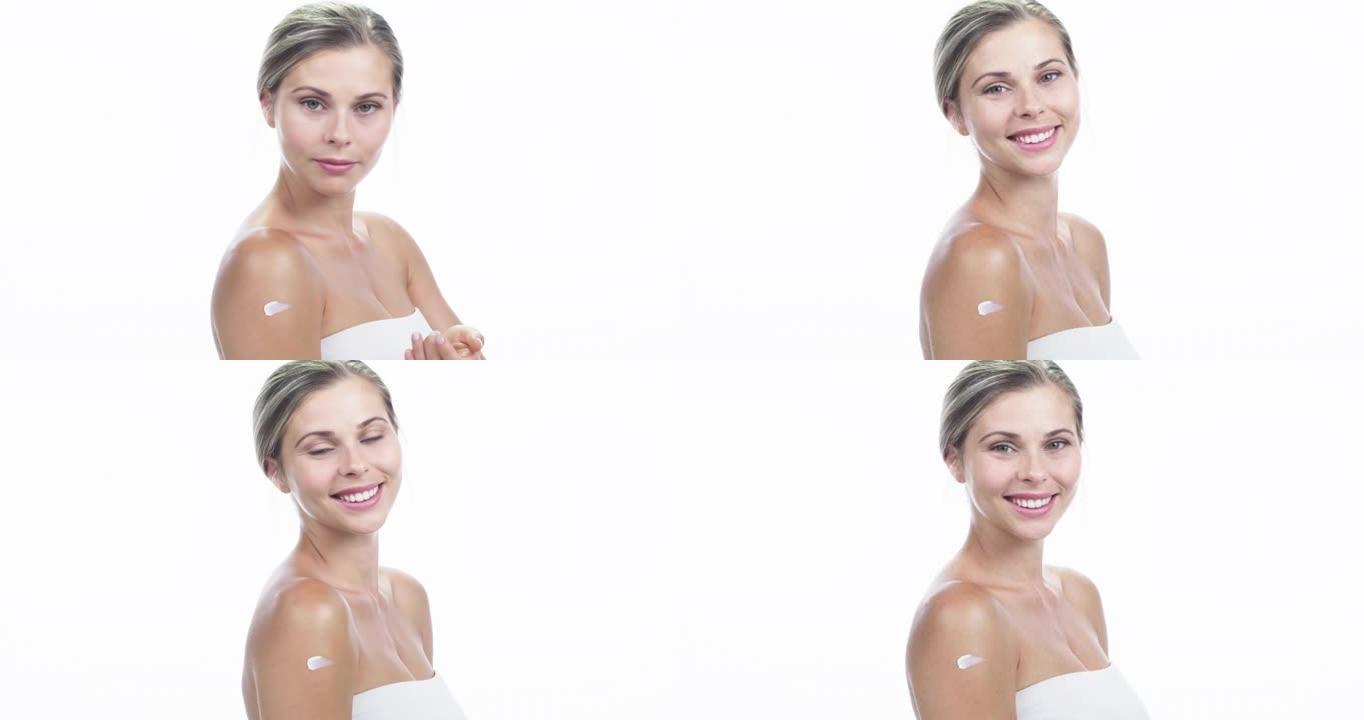 4k视频片段，一位迷人的年轻女子在白色工作室背景下使用保湿霜