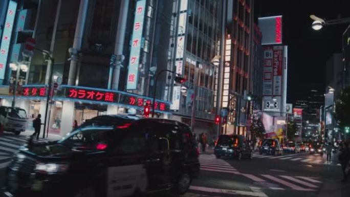 行人在东京新宿过马路。歌舞uki-cho娱乐和红灯区的拥挤人群和游客穿越道路。交通汽车和跨交叉路口的