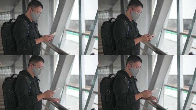 一名戴着防护口罩的亚洲华人男子行走在城市桥梁上，用智能手机手机应用查看金融股市场分析，受新冠肺炎疫情