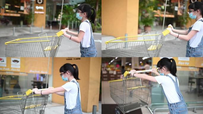 一位亚洲华裔年轻女孩从超市停车场推着手推车购物
