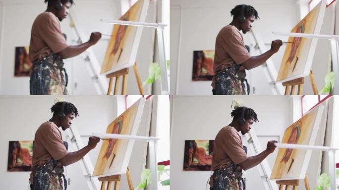 非裔美国男艺术家戴着耳机在艺术工作室的画布上绘画