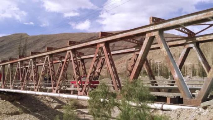 一辆汽车穿过阿根廷安第斯山脉胡胡伊省蒂尔卡拉的一座老桥。