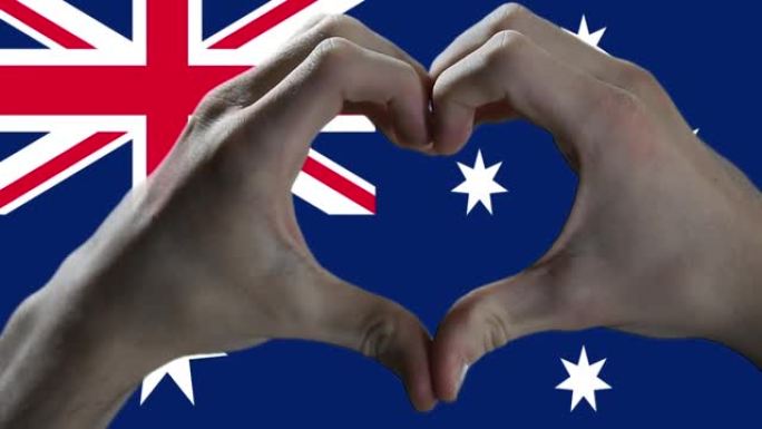 男人的手使心脏在澳大利亚国旗上签名。特写。
