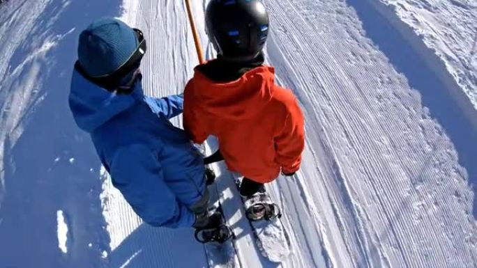 在美丽的晴天，滑雪板上的朋友在滑雪缆车上坡
