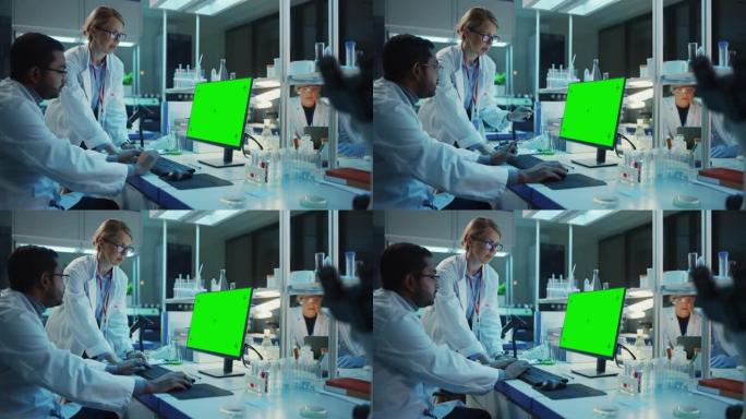 女研究科学家在带有绿屏模型的台式计算机旁边与生物工程师进行了对话。他们在现代科学实验室中查看计算机模