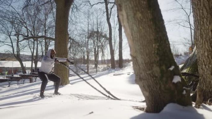 男人使用战斗绳索，冬天在户外健身房锻炼