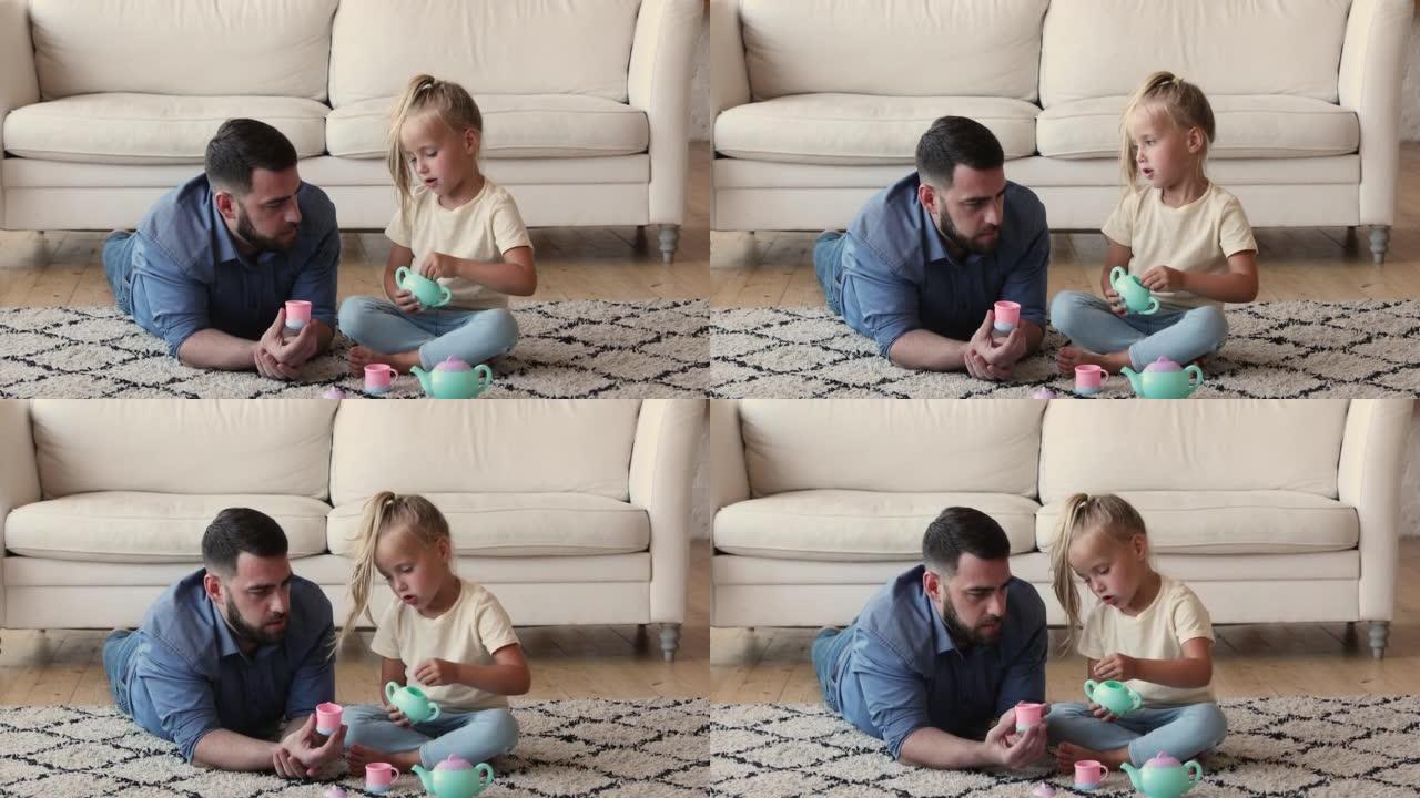 小女孩坐在地毯上和爸爸玩茶话会