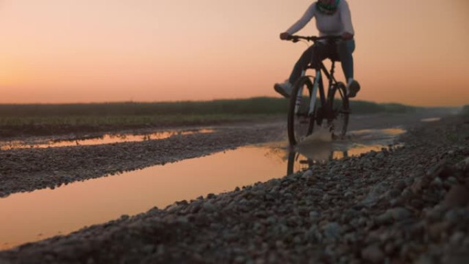女子骑自行车的人在潮湿的道路上骑自行车