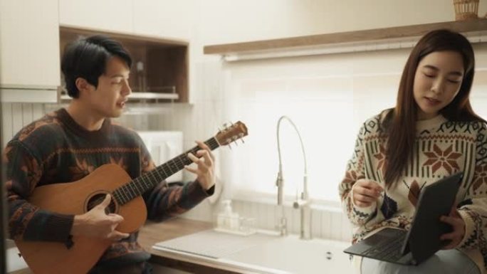 年轻夫妇在厨房一起唱歌玩得开心。