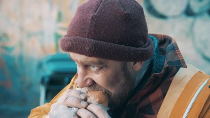 一个无家可归的人正在特写镜头中吃汉堡