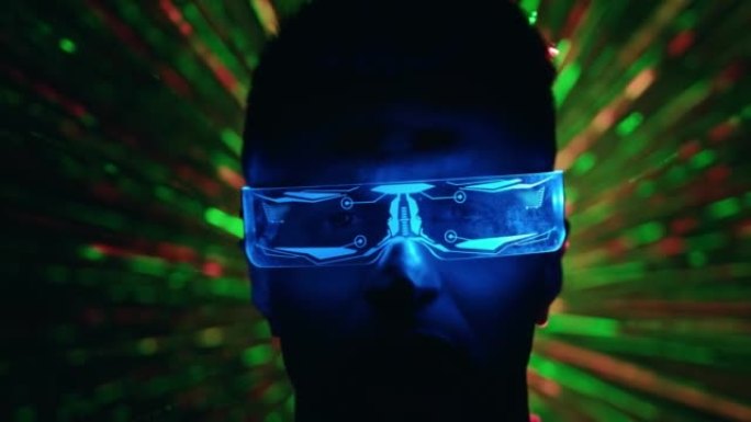 在彩色光线背景下，一个戴着未来派眼镜的男人的特写镜头