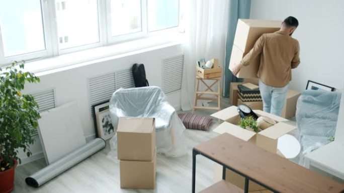 年轻的搬运工将纸板箱带入现代新公寓的高角度视图