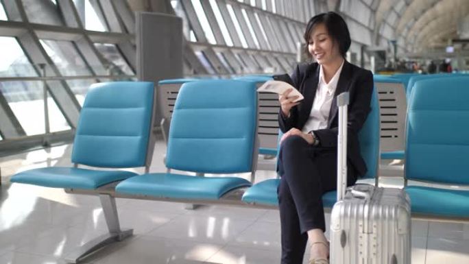 坐在机场候机室的女商人用手机拿着行李