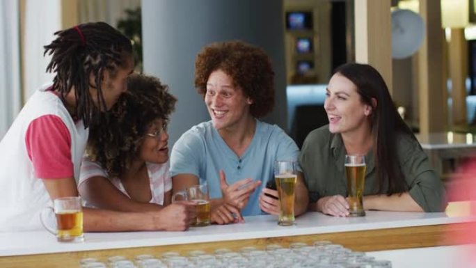 一群快乐的朋友在酒吧喝啤酒和使用智能手机
