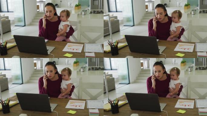 白人母亲在家工作时抱着婴儿并在智能手机上聊天