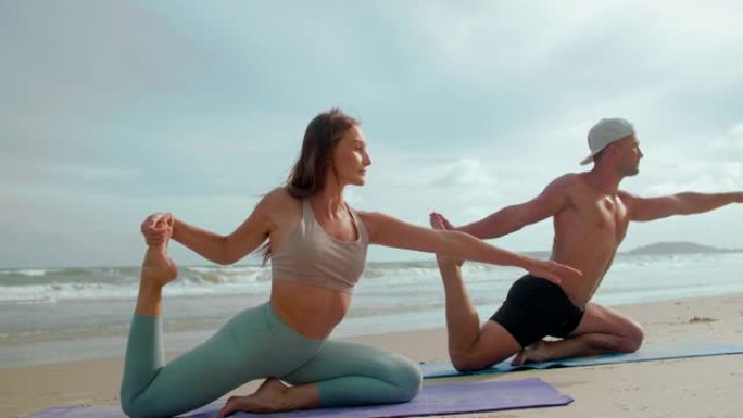 年轻夫妇在沙滩上锻炼，瑜伽，伸展身体