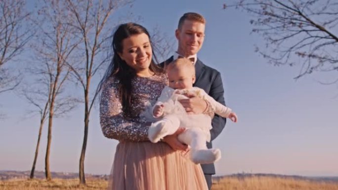 新娘在草地上站在新郎旁边时抱着女婴