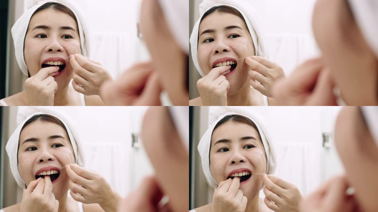 亚洲妇女在家里的浴室里用牙线洁牙