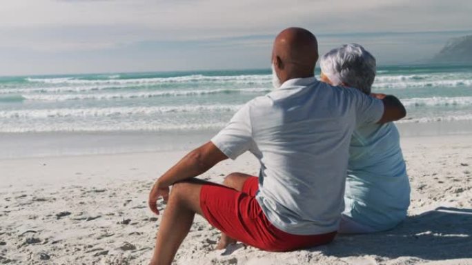 老年非裔美国夫妇坐在沙滩上拥抱