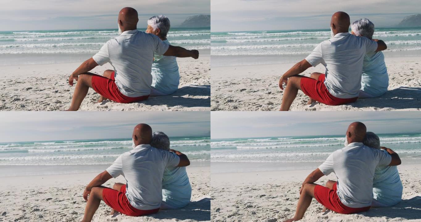 老年非裔美国夫妇坐在沙滩上拥抱