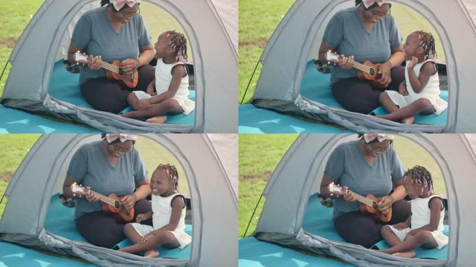 SLO MO快乐的妈妈和她的女儿在公园的帐篷里弹吉他尤克里里琴