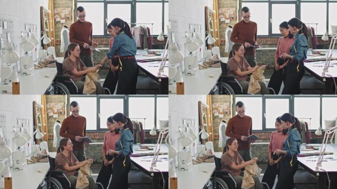 坐在轮椅上的女裁缝向时装设计师展示服装