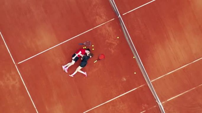 一对夫妇躺在网球场上接吻的俯视图