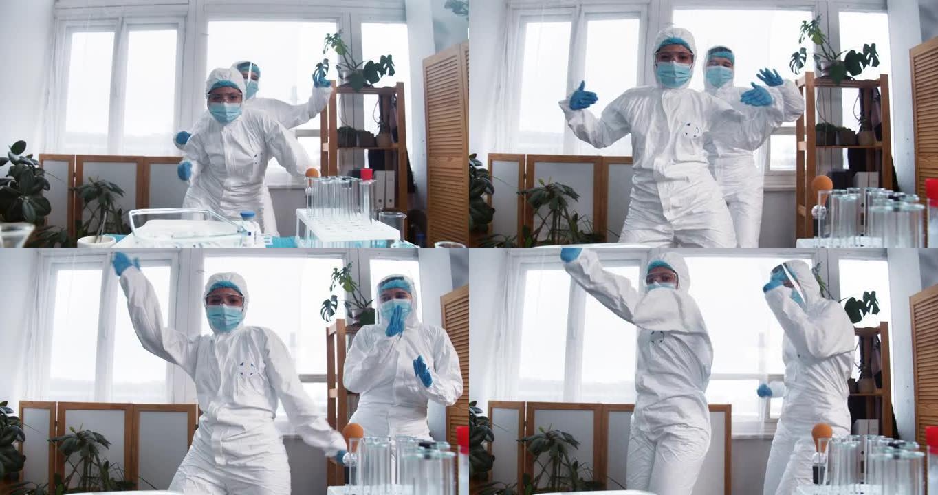 新型冠状病毒肺炎大流行结束。两个快乐兴奋有趣的女医生，穿着防护服的科学家们做庆祝舞蹈。