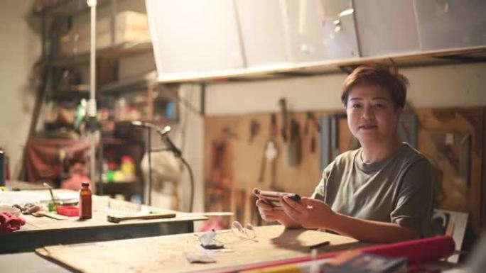 亚洲中国成熟女焊工在车间工作，看着相机微笑