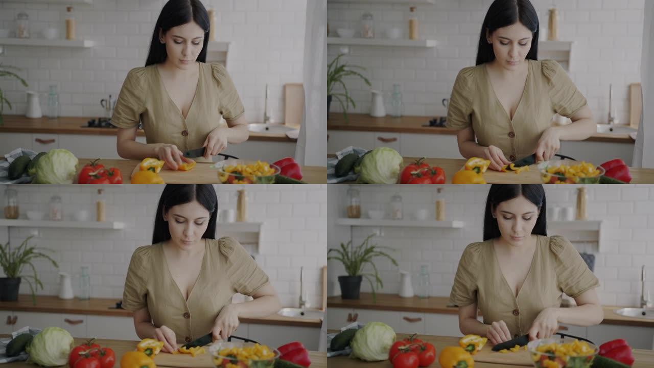 漂亮的年轻女子在公寓厨房准备蔬菜沙拉切割产品
