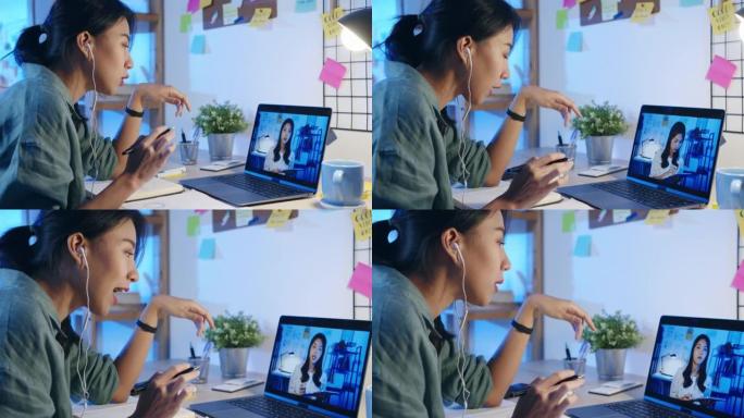 亚洲女商人使用笔记本电脑与同事讨论客厅视频通话会议的计划。