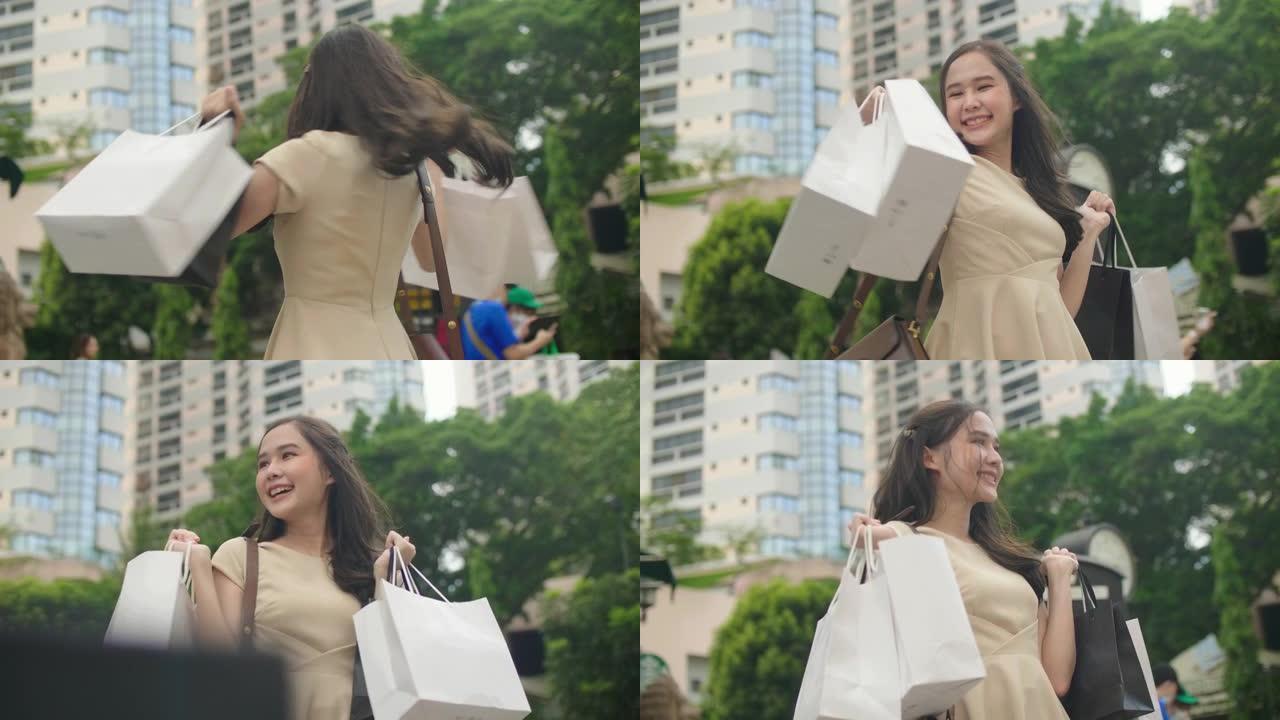 年轻的亚洲女人高兴地拿着她的购物袋