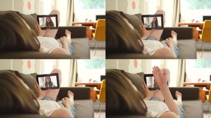4k视频片段，一名妇女躺在沙发上使用数字平板电脑进行视频通话