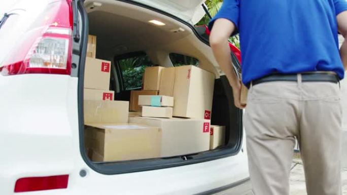 戴着口罩的年轻亚洲志愿者送货员在汽车中运送包裹纸盒包装并寄给客户。
