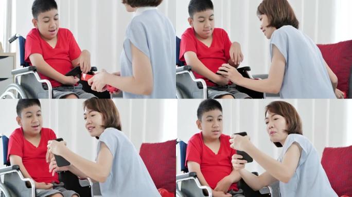 10-11岁的亚洲残疾男孩坐在轮椅上与母亲或护理人员一起在家通过smatphone学习在线课程。残疾