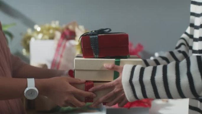 女孩手的特写赠送礼物盒冬季圣诞装饰品在桌子上。