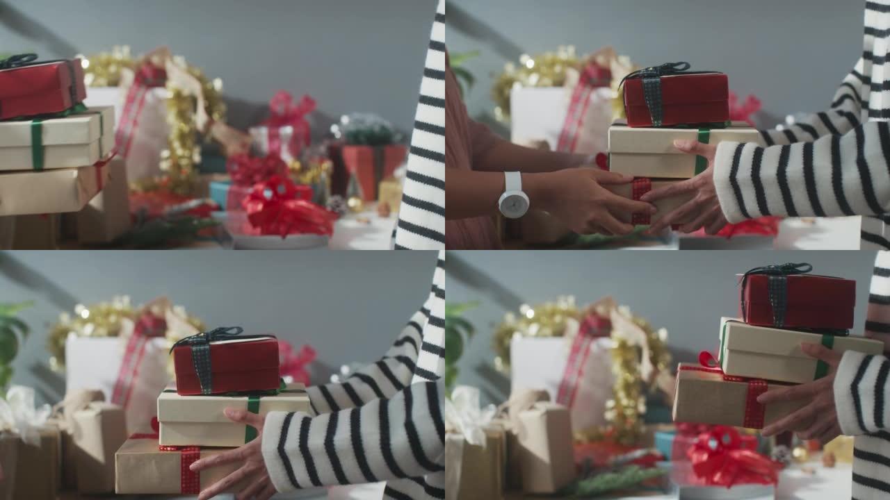 女孩手的特写赠送礼物盒冬季圣诞装饰品在桌子上。