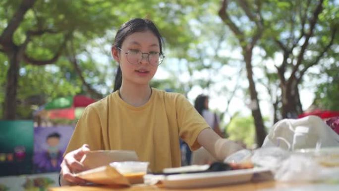 4k新正常饮食。亚洲年轻少女在户外市场午餐前脱下口罩