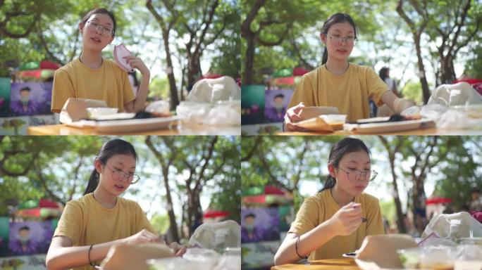 4k新正常饮食。亚洲年轻少女在户外市场午餐前脱下口罩