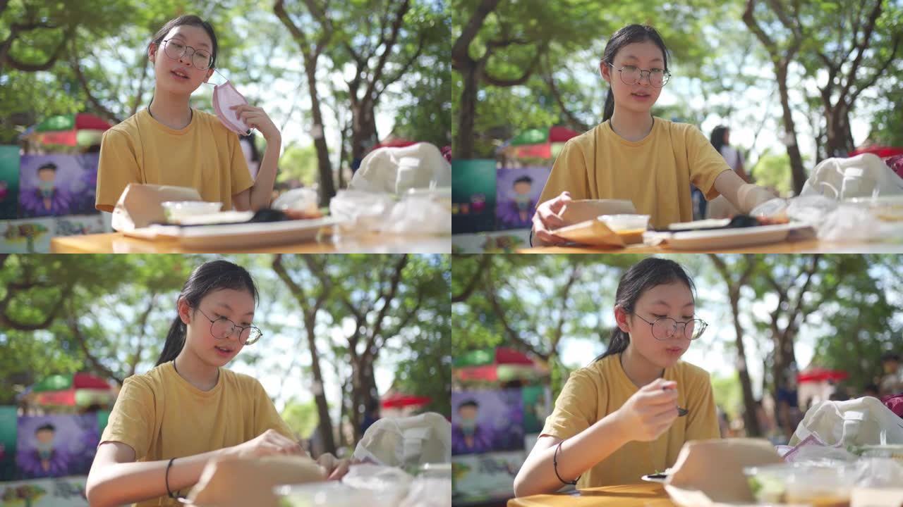 4k新正常饮食。亚洲年轻少女在户外市场午餐前脱下口罩