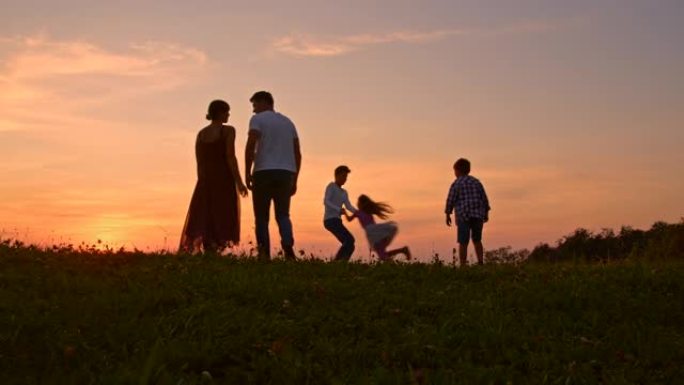 SLO MO Young家庭与三个孩子一起在日落时在草地上度过时光