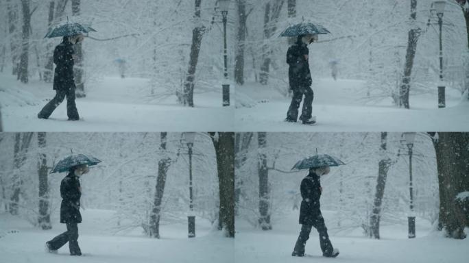 慢动作: 穿着冬衣和背着雨伞的女人在暴风雪中行走