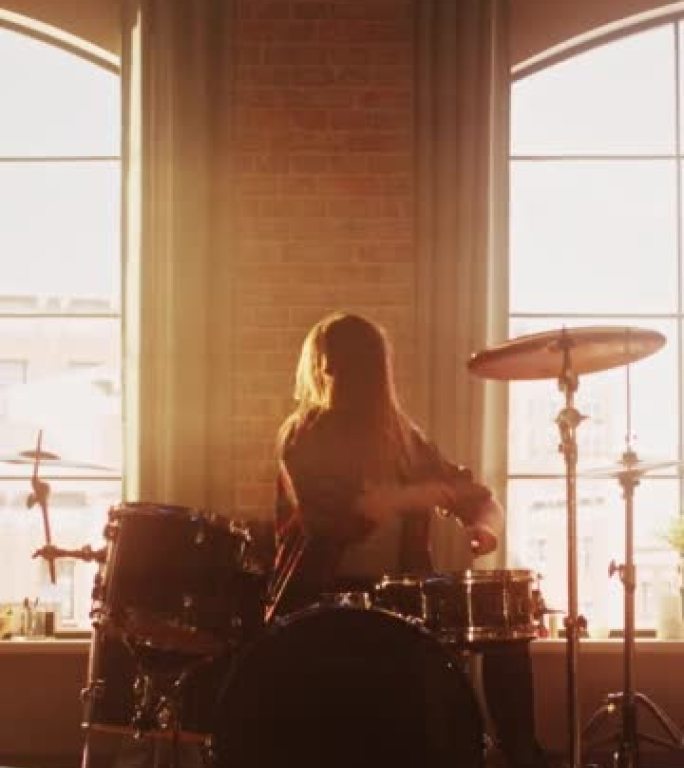 垂直屏幕: 富有表现力的鼓手女孩在充满灯光的阁楼音乐排练室里打鼓。摇滚乐队音乐艺术家学习新鼓独奏。