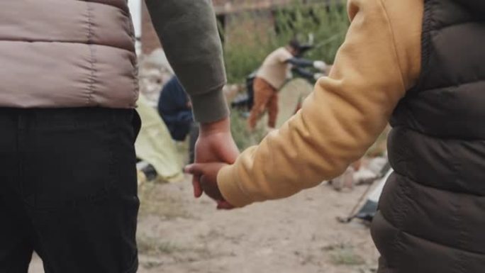 难民女孩在帐篷城市散步时手牵着手