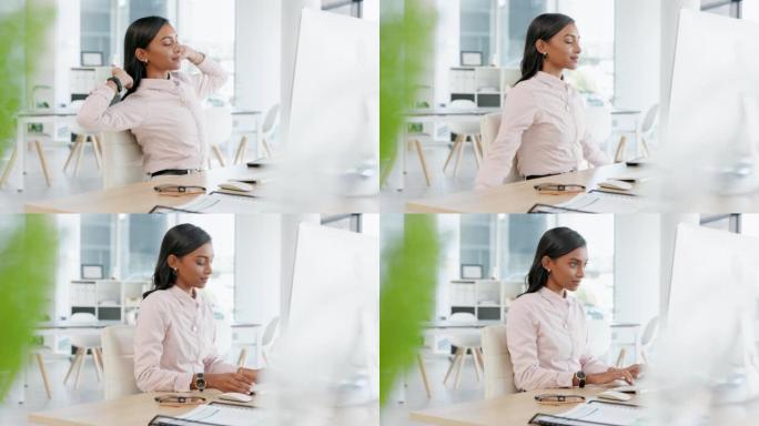 年轻的女商人在办公室里独自在台式计算机上打字之前先伸展身体。一名印度女公司工人在完成个人电脑的最后期