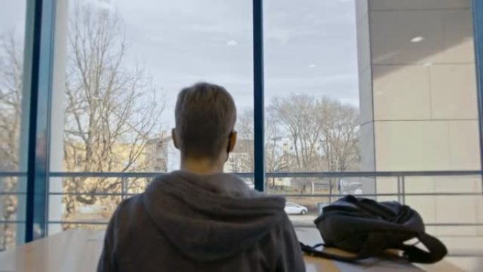 SLO MO学生在图书馆书籍过道尽头的桌子上使用笔记本电脑